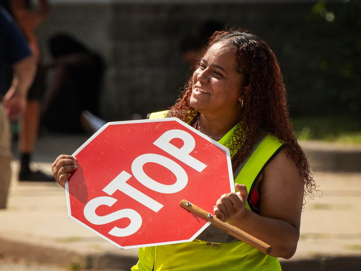 Crossing guard Veronica Justiniano fans herself with her sign as she waits for the weather-related early dismissal at City View Discovery School.