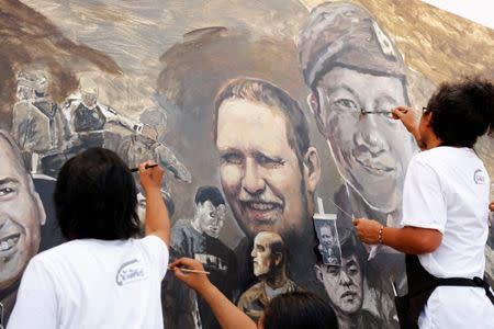 The portrait of Samarn Kunan (R), a former Thai navy SEAL who died during a recuse mission to save 12 soccer boys and their coach at Tham Luang cave complex, is painted on a giant painting in Chiang Rai, Thailand July 14, 2018. REUTERS/Tyrone Siu