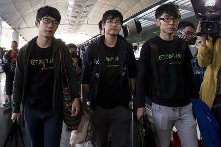 Hong Kong Federation of Students leader Alex Chow (C), committee members Nathan Law (L) and Eason Chung react after being refused to board the plane at the Hong Kong International Airport November 15, 2014. REUTERS/Tyrone Siu