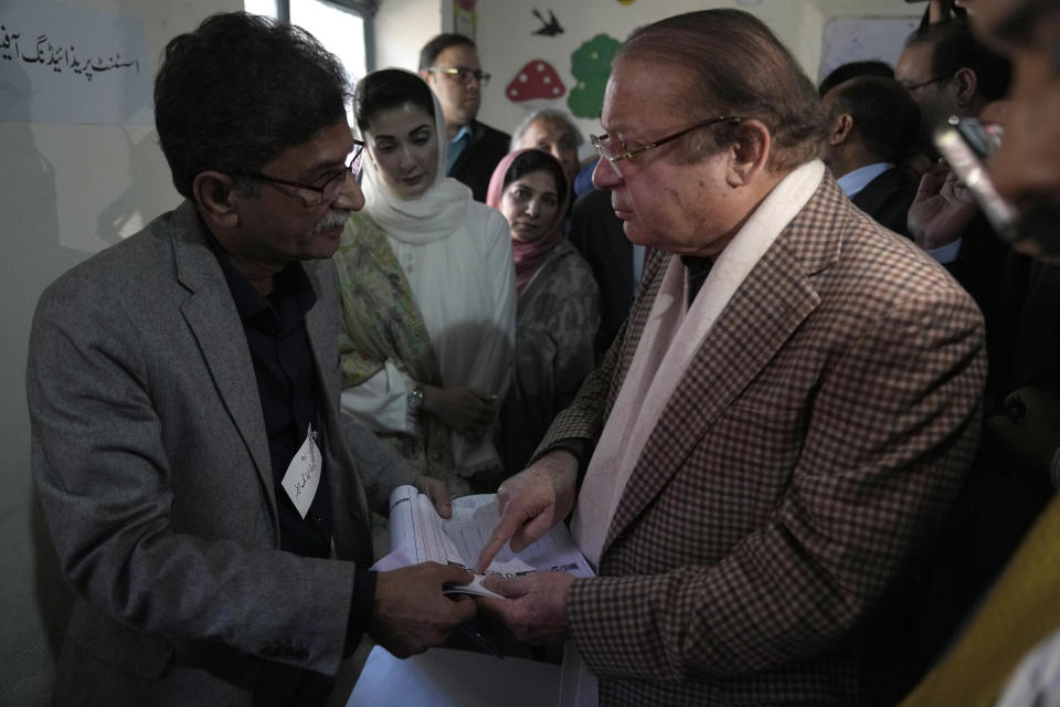 Pakistan's former Prime Minister Nawaz Sharif, right, talks to an officer of polling staff before casting his vote at a polling station for the country's parliamentary elections, in Lahore, Pakistan, Thursday, Feb. 8, 2024. Pakistanis lined braved cold winter weather and the threat of violence to vote for a new parliament Thursday, a day after twin bombings claimed at least 30 lives in the worst election-related violence ahead of the contested elections. (AP Photo/K.M. Chaudary)