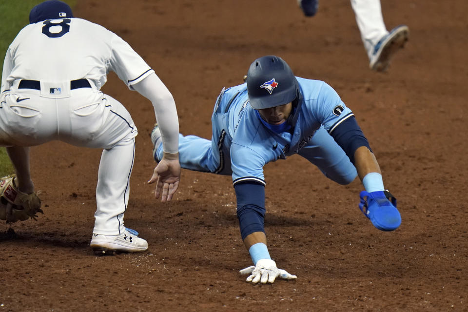 Toronto Blue Jays' Lourdes Gurriel Jr. dives back safely ahead of the tag by Tampa Bay Rays' Brandon Lowe (8) on a pickoff attempt during the ninth inning of a baseball game Saturday, Aug. 22, 2020, in St. Petersburg, Fla. (AP Photo/Chris O'Meara)