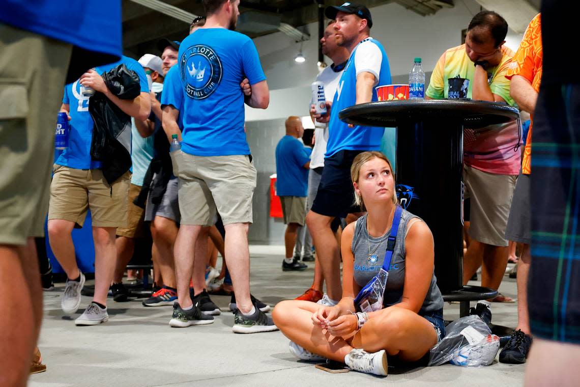 Hannah Bernard, of Matthews, sits under a table as fans are told to shelter in place during a thunderstorm which delayed the game between between Charlotte FC and Columbus Crew at Bank of America Stadium in Charlotte, N.C., Saturday, July 30, 2022.