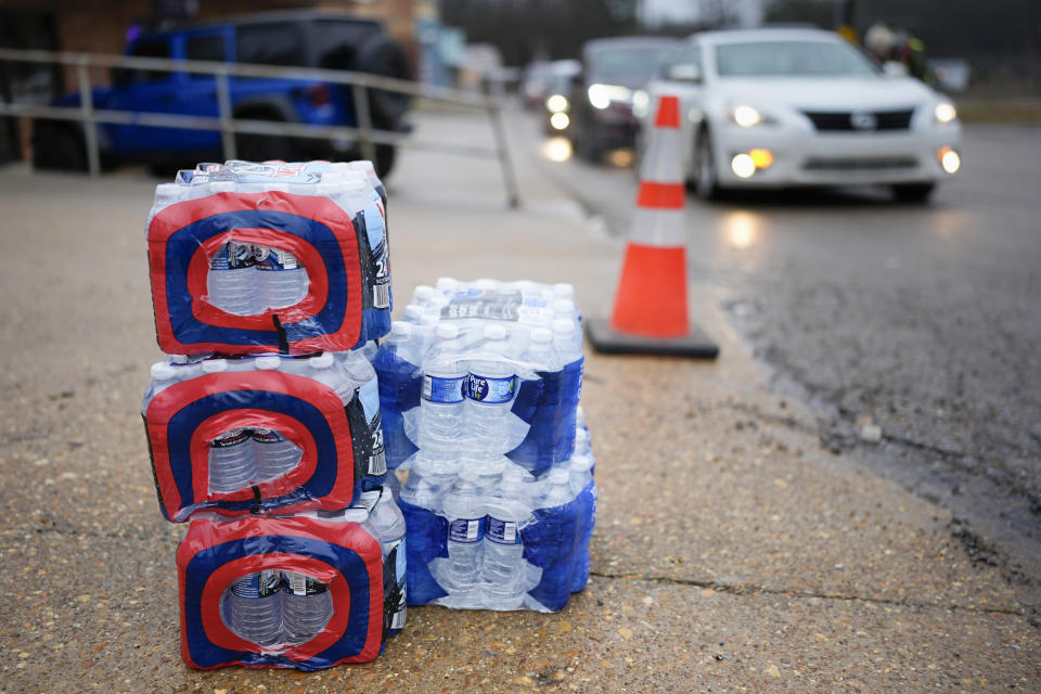 Bottled water rests on the pavement outside the Mason Fire Department Wednesday, Jan. 24, 2024, in Mason, Tenn. A winter storm brought sub-freezing temperatures and snow to Mason and the rest of Tennessee last week. The cold caused the town's pipes to freeze over and break, creating leaks that lowered water pressure. The cold exposed major problems with a water system that dates back to the 1950s. (AP Photo/George Walker IV)