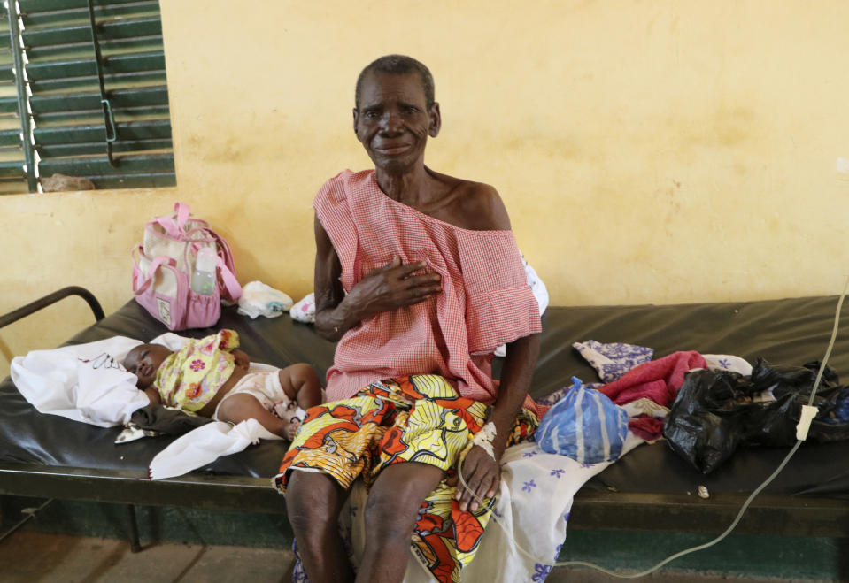 A woman sits on a bed in a small clinic in Zeguedessin village on the outskirts of Burkina Faso's capital, Ouagadougou, receiving medical treatment on Thursday Oct. 8, 2020. The hospital's solar fridge has been broken for a year meaning there is less space in the hospital to store large amounts of vaccines. The vaccine cold chain hurdle is just the latest disparity of the pandemic weighted against the poor, who more often live and work in crowded conditions that allow the virus to spread, have little access to medical oxygen vital to COVID-19 treatment, and whose health systems lack labs, supplies or technicians to carry out large-scale testing. (AP Photo/Sam Mednick)