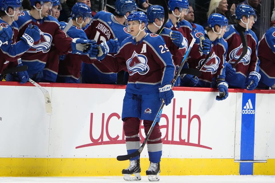 Colorado Avalanche center Nathan MacKinnon, front, is congratulated as he passes the team box after scoring a goal in the second period of an NHL hockey game against the Washington Capitals Wednesday, Jan. 24, 2024, in Denver. (AP Photo/David Zalubowski)