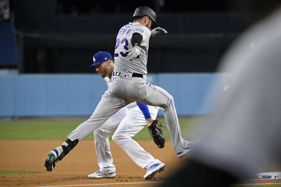 Colorado Rockies' Kris Bryant, right, is safe at first after knocking the ball and glove out of the hand of Los Angeles Dodgers first baseman Freddie Freeman during the first inning of a baseball game Monday, April 3, 2023, in Los Angeles. (AP Photo/Mark J. Terrill)