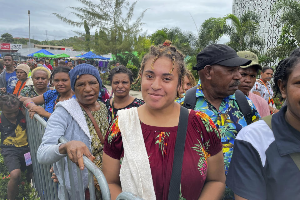Seventeen year-old student Naomi Kipoi, center, visits at Gordon's Market in Port Moresby, Papua New Guinea, Monday, May 22, 2023. The United States is scheduled to sign a new security pact with Papua New Guinea on Monday as it competes with China for influence in the Pacific. Kipoi opposes the security pact between the U.S. and Papua New Guinea. (AP Photo/Nick Perry)