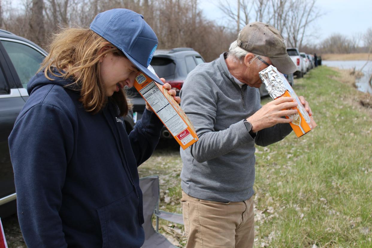 Preparing to view the solar eclipse at the Erie State Game Area, Lars Wilson, 13, left, and his grandfather, Robert Miner, demonstrate how their homemade pinhole cameras work.