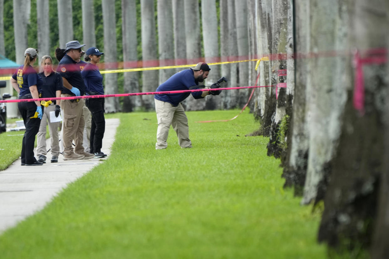 A law enforcement official takes photos as other investigators survey the area.