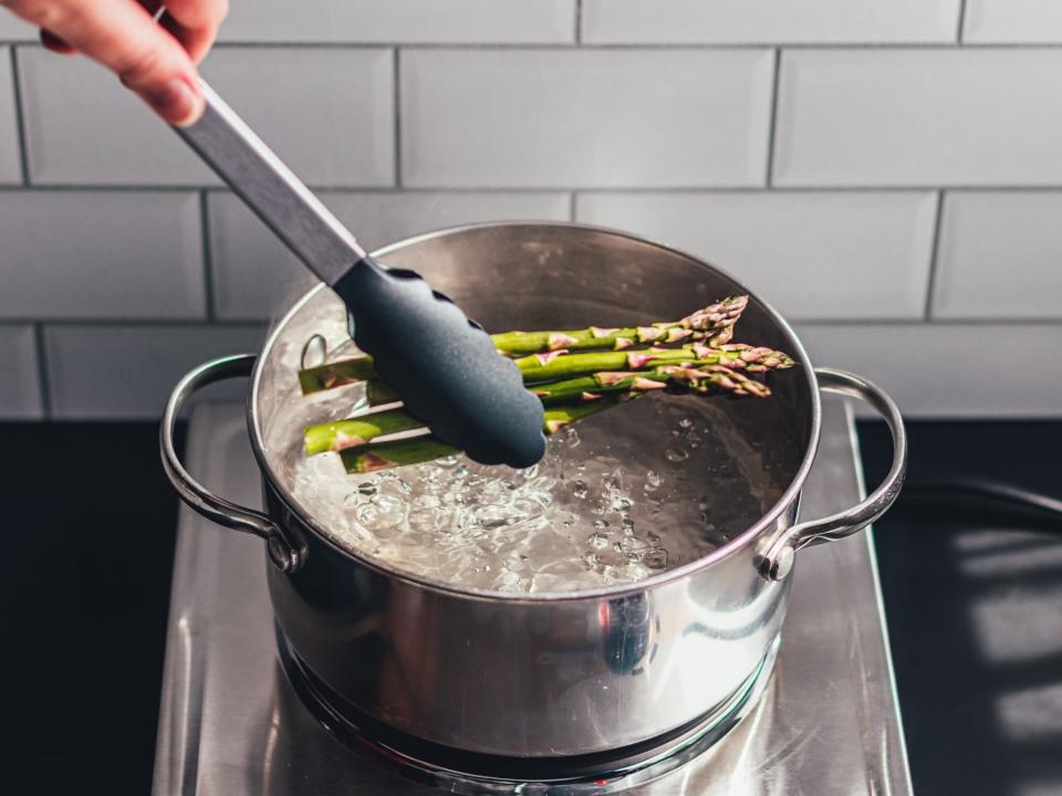 several spears of asparagus in a pot of boiling water