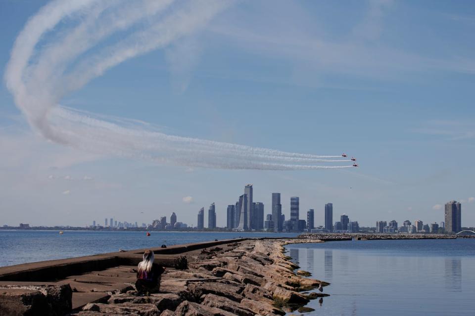 A spectator watches the Northern Star demonstration team fly above the Toronto lakeshore on Sept. 2, 2022. The Canadian International Airshow, which runs over Labour Day long weekend, will begin on Saturday, Sept. 2, 2023.