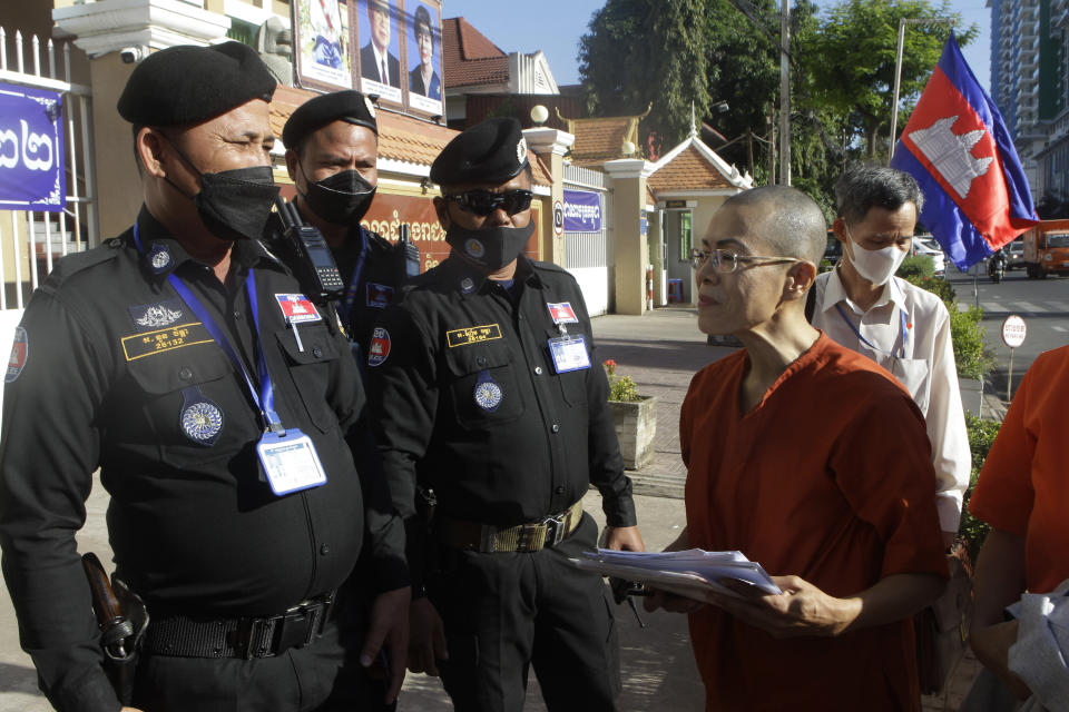 Theary Seng, right, a Cambodian-American lawyer, dressed in a prison-style orange outfit, talks with court securities as she arrived at Phnom Penh Municipal Court in Phnom Penh, Cambodia, Tuesday, Jan. 4, 2022. Cambodian security forces on Tuesday briefly detained Theary, a prominent rights activist, as she walked barefoot near the prime minister’s residence in Phnom Penh, wearing the orange outfit and Khmer Rouge-era ankle shackles. She was released, shortly afterwards, and arrived at the Phnom Penh court for the resumption of her trial on treason charges. (AP Photo/Heng Sinith)
