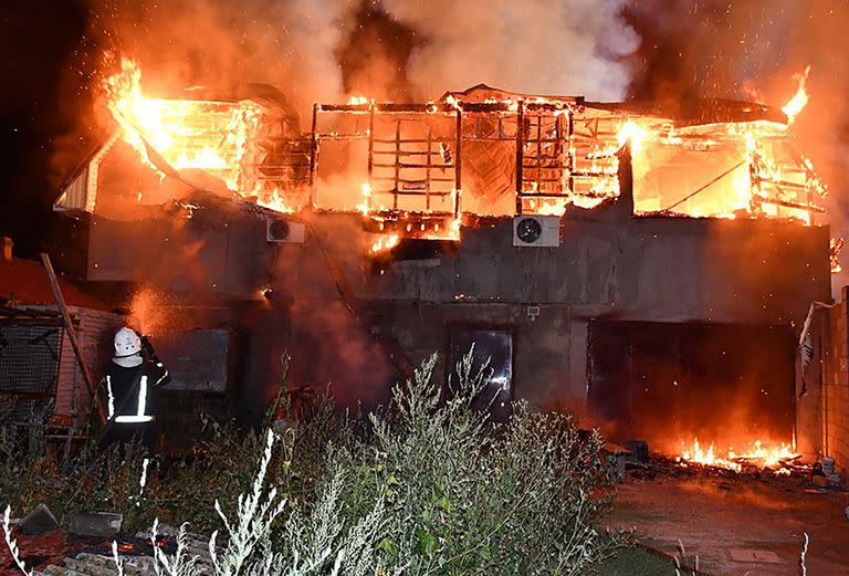 Esta fotografía tomada y difundida por el Servicio de Emergencias de Ucrania el 25 de julio de 2022, muestra a un bombero enfrentándose al fuego frente a un edificio residencial en llamas tras un bombardeo en la región de Mykolaiv, en medio de la invasión rusa de Ucrania.