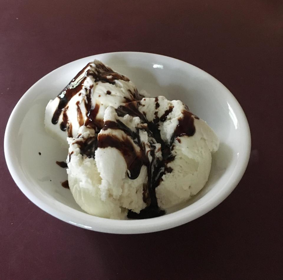 A bowl of vanilla ice cream topped with chocolate syrup