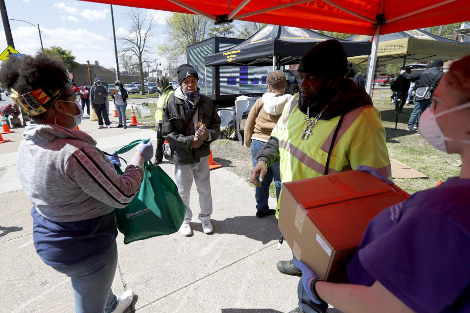 In this Tuesday, May 12, 2020, photo, Norman Harris, center, waits for a box and bag of food at a giveaway sponsored by the Greater Chicago Food Depository in the Auburn Gresham neighborhood of Chicago. Across the country, food insecurity is adding to the anxiety of millions of people, according to a new survey that finds 37 percent of unemployed Americans ran out of food in the past month, while 46 percent worried that they would. The nationwide unemployment rate on Friday was 14.7 percent, the highest since the Great Depression.(AP Photo/Charles Rex Arbogast)