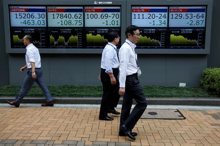 Passersby walk past in front of electronic boards showing Japan's Nikkei share average (L), the Japanese yen's exchange rate against the U.S. dollar (C), British pound (R) and Euro (2nd R) outside a brokerage in Tokyo, Japan, July 6, 2016. REUTERS/Issei Kato