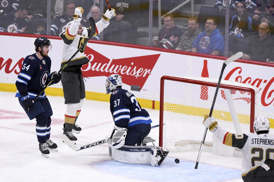 Vegas Golden Knights' Mark Stone (61) celebrates the goal by Jonathan Marchessault, not shown, on Winnipeg Jets goaltender Connor Hellebuyck (37) during the third period of an NHL Hockey game in Winnipeg, Manitoba on Tuesday, Dec. 13, 2022. (Fred Greenslade/The Canadian Press via AP)