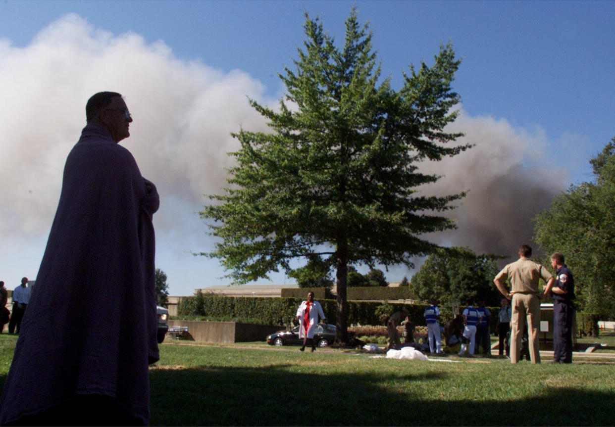 Pentagon workers watch the building burn after a plane crashed into it September11, 2001 in Arlington VA.