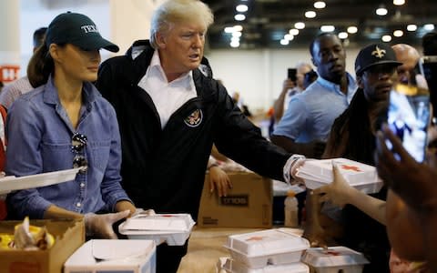 President Donald Trump and first lady Melania Trump help volunteers hand out meals during a visit with flood survivors of Hurricane Harvey at a relief centre in Houston - Credit: Reuters