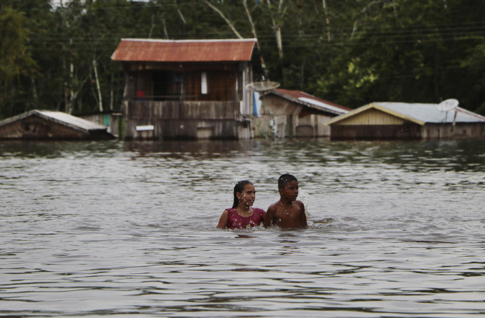 Residents move through on a flooded street in Anama, Amazonas state, Brazil, Thursday, May 13, 2021. (AP Photo/Edmar Barros)