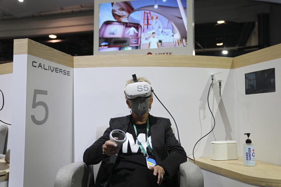 FILE - Kelly Taylor tries out a metaverse virtual shopping experience at the LOTTE Data Communication booth during the CES tech show Wednesday, Jan. 5, 2022, in Las Vegas. The thousands of people who gathered in Las Vegas for this week's CES gadget show were a fraction of the usual crowd for the influential tech conference, the event's organizer said Friday, Jan. 7. The Consumer Technology Association said on the show's closing day that more than 40,000 people attended the multi-day event on the Las Vegas Strip. (AP Photo/Joe Buglewicz, File)