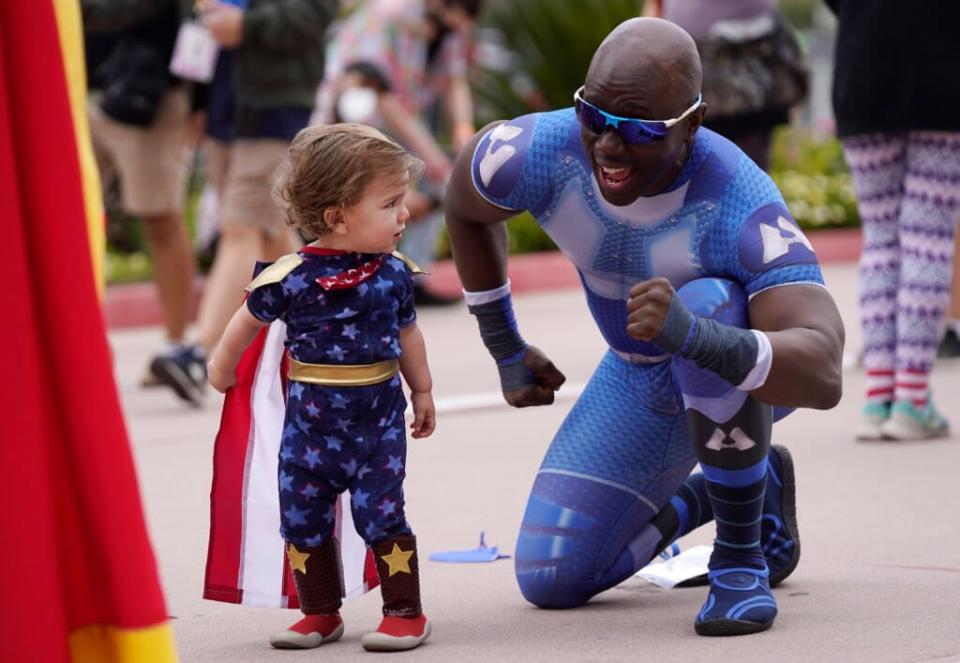 Jay Acey, right, dressed as A-Train from the television series “The Boys,” mingles with Maddox Cruz, 1, of Orange, Calif., outside Preview Night at the 2022 Comic-Con International at the San Diego Convention Center, Wednesday, July 20, 2022, in San Diego. (AP Photo/Chris Pizzello)