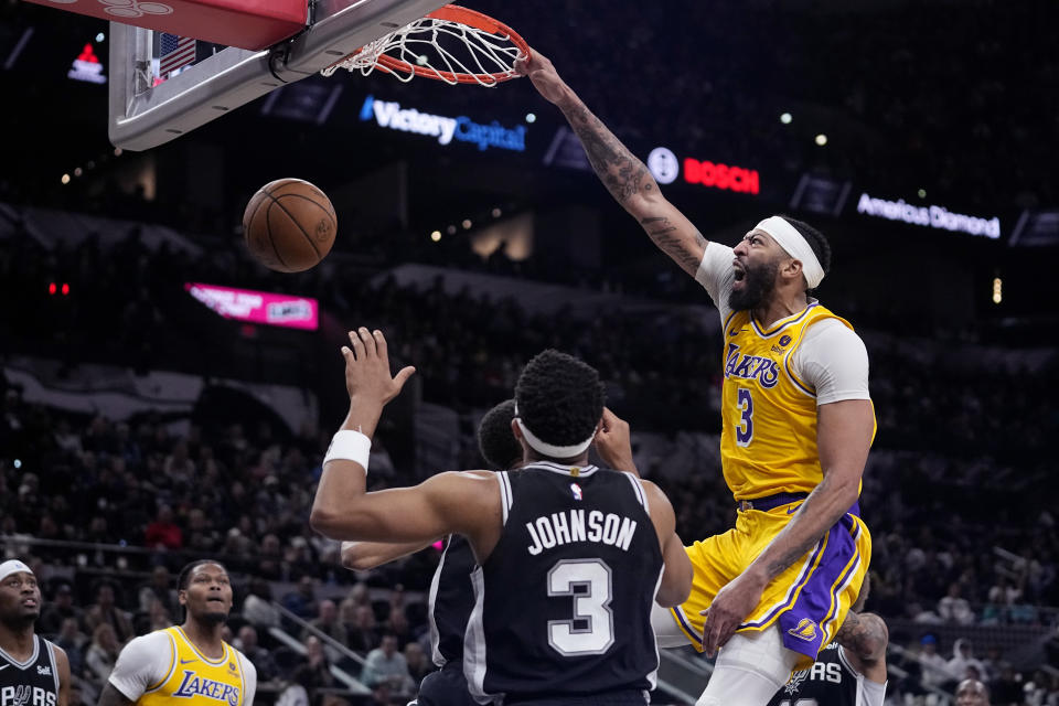 Los Angeles Lakers forward Anthony Davis (3) reacts as he scores over San Antonio Spurs center Victor Wembanyama (1) and forward Keldon Johnson (3) during the first half of an NBA basketball game in San Antonio, Wednesday, Dec. 13, 2023. (AP Photo/Eric Gay)