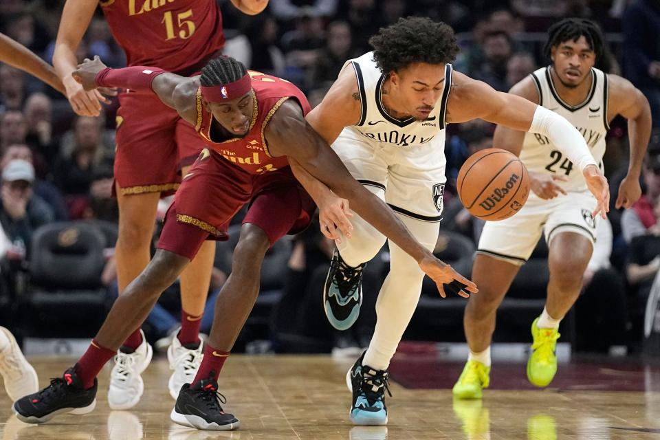 Cleveland Cavaliers guard Caris LeVert, left, and Brooklyn Nets forward Jalen Wilson, right, reach for the ball in the first half of an NBA basketball game, Sunday, March 10, 2024, in Cleveland. (AP Photo/Sue Ogrocki)