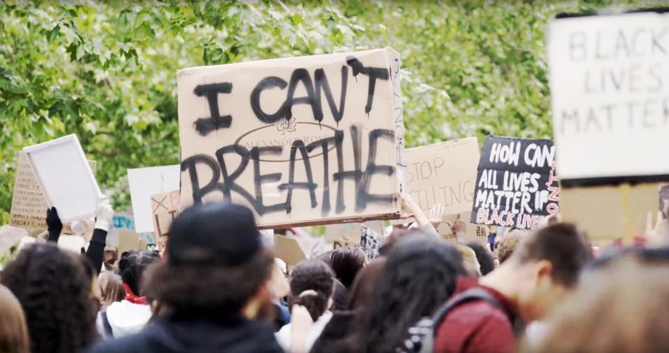 Protesters with a signs that read "Black Lives Matter" and "I Can't Breather"