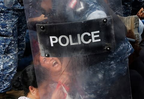 Riot police remove an anti-government protester who is blocking a main highway with her body, in Beirut, Lebanon - Credit: Hussein Malla&nbsp;/AP