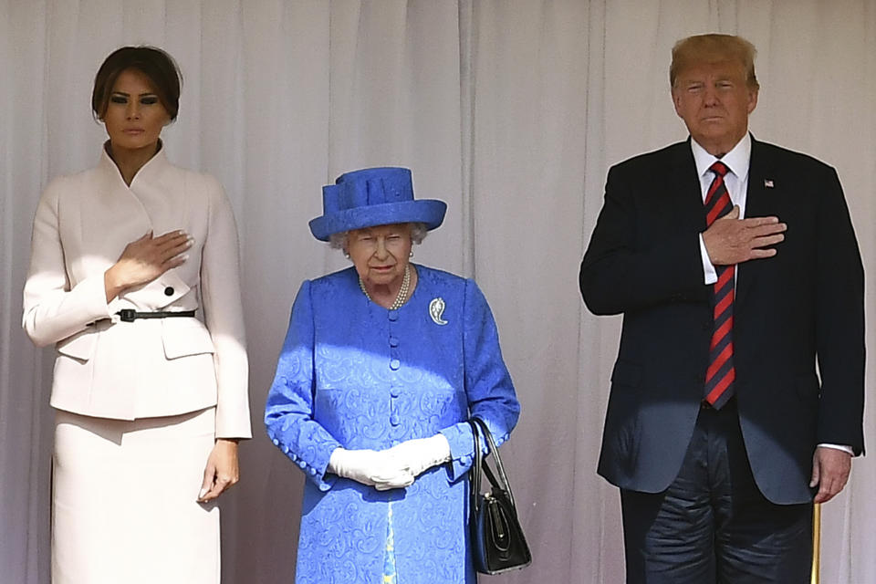 <p>Britain’s Queen Elizabeth II, center, stands with President Donald Trump and first lady Melania on the dias in the Quadrangle as they listen to a band of guardsmen play the U.S. national anthem during a ceremonial welcome at Windsor Castle, Friday, July 13, 2018 in Windsor, England. (Photo: Ben Stansall/Pool Photo via AP) </p>