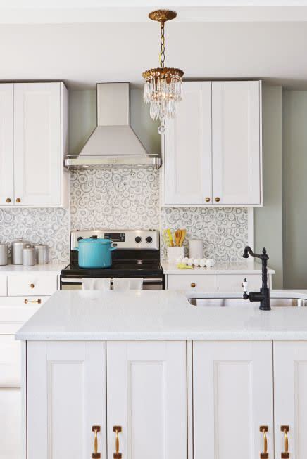 <p>The neutral circle pattern, brass accents and ornate pendant add to this kitchen's high-end look. The backsplash adds minimal grandeur to the entire design scheme.<br></p>