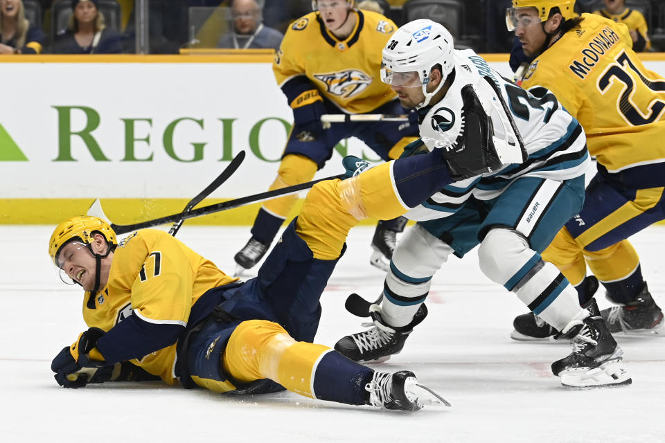 Nashville Predators right wing Michael McCarron, left, is tripped by San Jose Sharks defenseman Mario Ferraro (38) during the second period of an NHL hockey game Saturday, Oct. 21, 2023, in Nashville, Tenn. (AP Photo/Mark Zaleski)