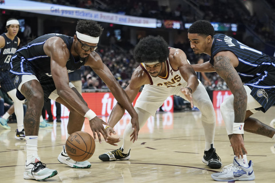 From left to right, Orlando Magic's Wendell Carter Jr., Cleveland Cavaliers' Jarrett Allen and Magic's Gary Harris battle for the ball in the second half of an NBA basketball game, Saturday, Nov. 27, 2021, in Cleveland. (AP Photo/Tony Dejak)