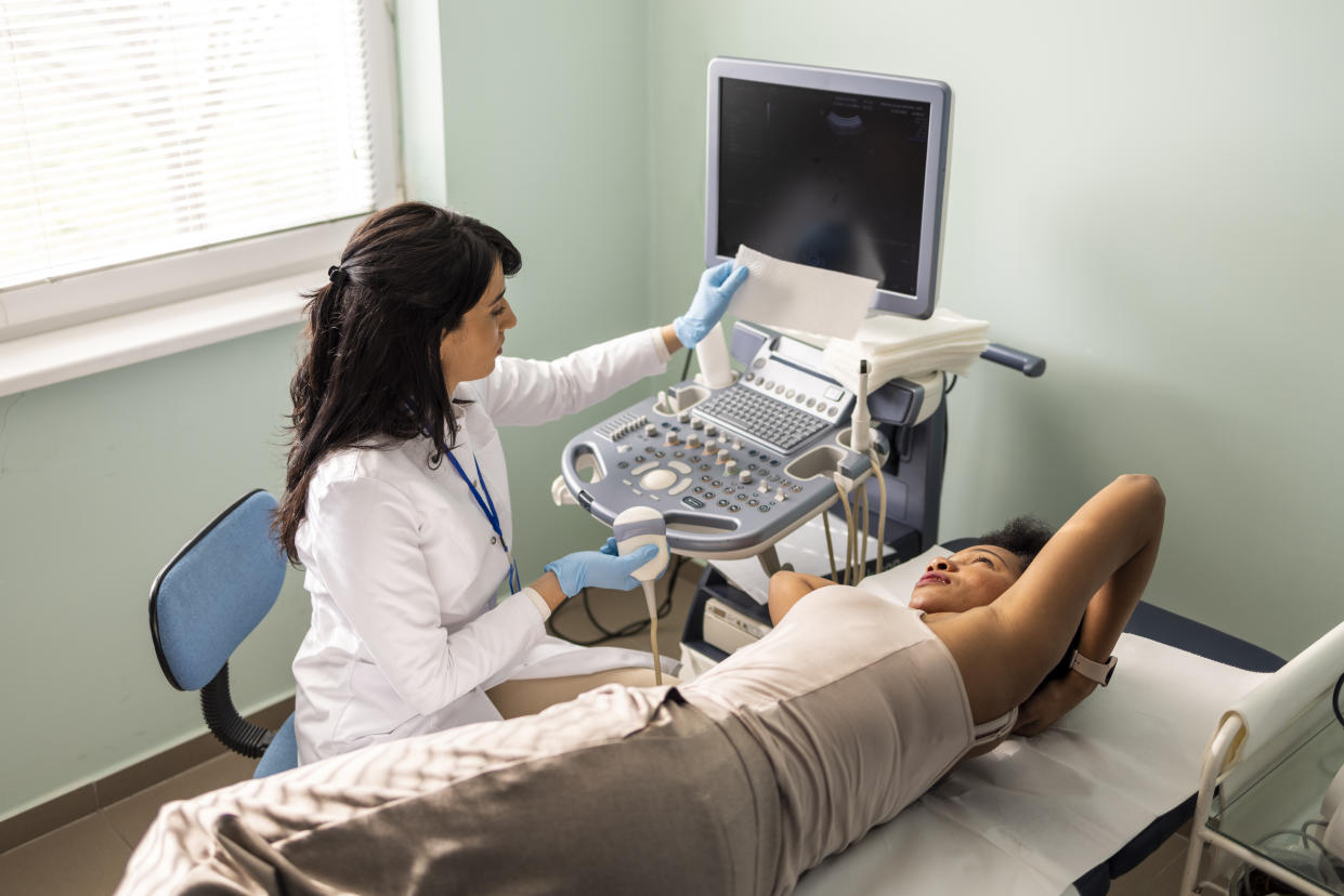 A sonographer performs an ultrasound scan on a woman's body.