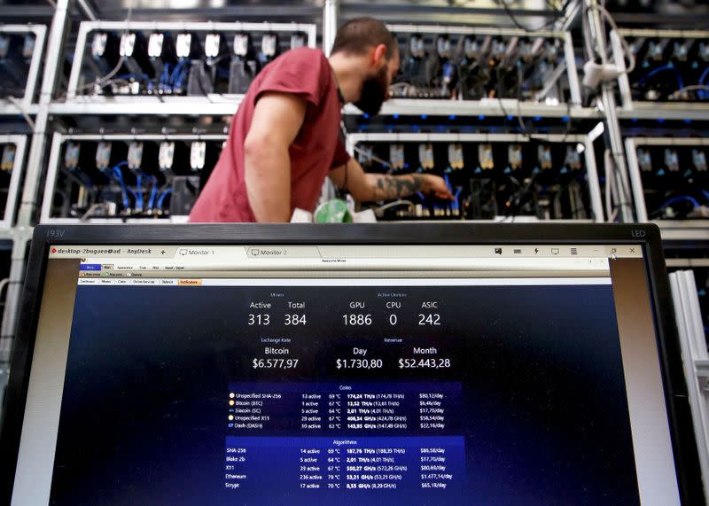 FILE PHOTO: An employee works on Bitcoin mining computer as a PC screen shows the fluctuations in Bitcoin exchange rates at Bitminer Factory in Florence