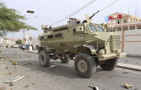 Soldiers from the African Union Mission in Somalia (AMISOM) drive their armoured personnel carrier (APC) past the scene of a suicide car explosion in front of the SYL hotel in the capital Mogadishu January 22, 2015. REUTERS/Feisal Omar