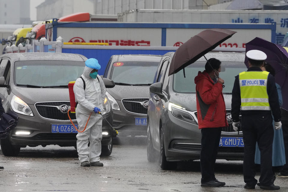 A worker in protective overall disinfects a vehicle from the World Health Organization convoy while they were visiting the Baishazhou wholesale market on the third day of field visit in Wuhan in central China's Hubei province on Sunday, Jan. 31, 2021. (AP Photo/Ng Han Guan)