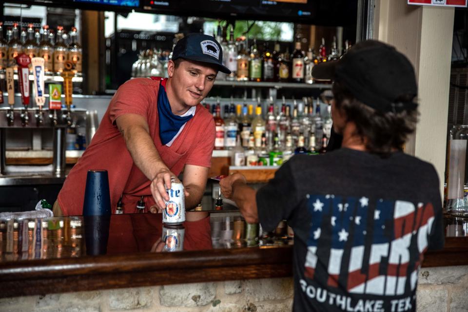 A bartender serves a drink to a customer at a bar in Austin, Texas on May 22, 2020. - Austin allowed bingo halls, bars and bowling alleys to reopen on Friday May 22. (Photo by Sergio Flores / AFP) (Photo by SERGIO FLORES/AFP via Getty Images)