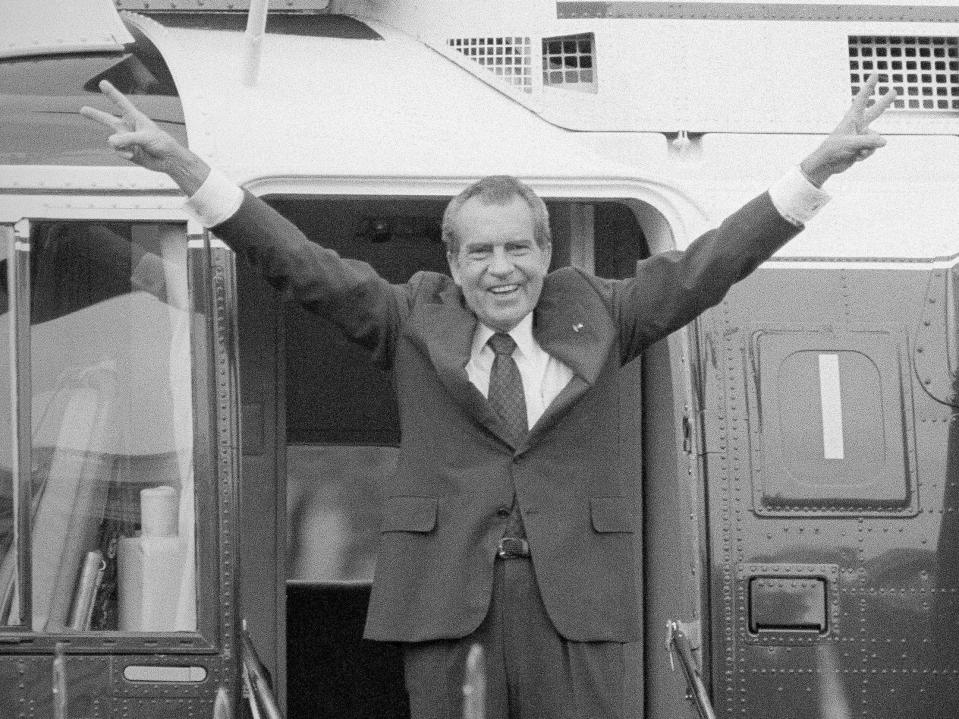 Richard Nixon says goodbye with a victorious salute to his staff members outside the White House as he boards a helicopter after resigning the presidency in 1974.