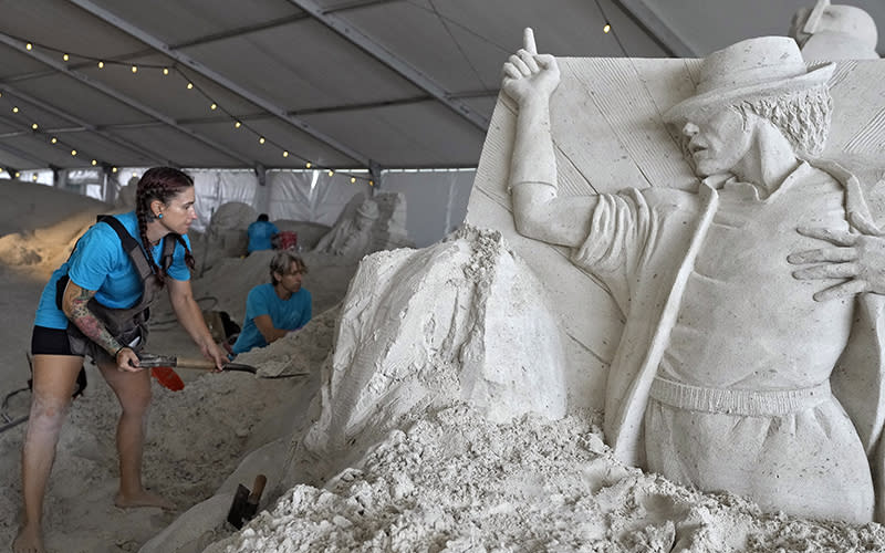 Melineige Beauregard, left, and Chris Guinto, both of Big Island, Hawaii, work on their sand sculptures depicting musicians