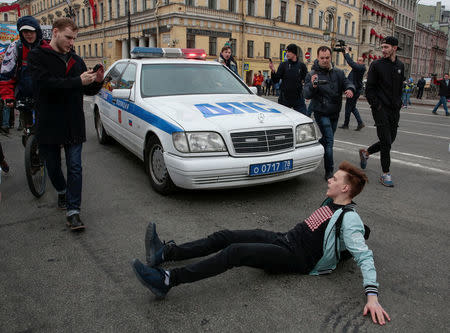 An opposition supporter tries to block a police car during a protest ahead of President Vladimir Putin's inauguration ceremony, Saint Petersburg, Russia May 5, 2018. REUTERS/Anton Vaganov