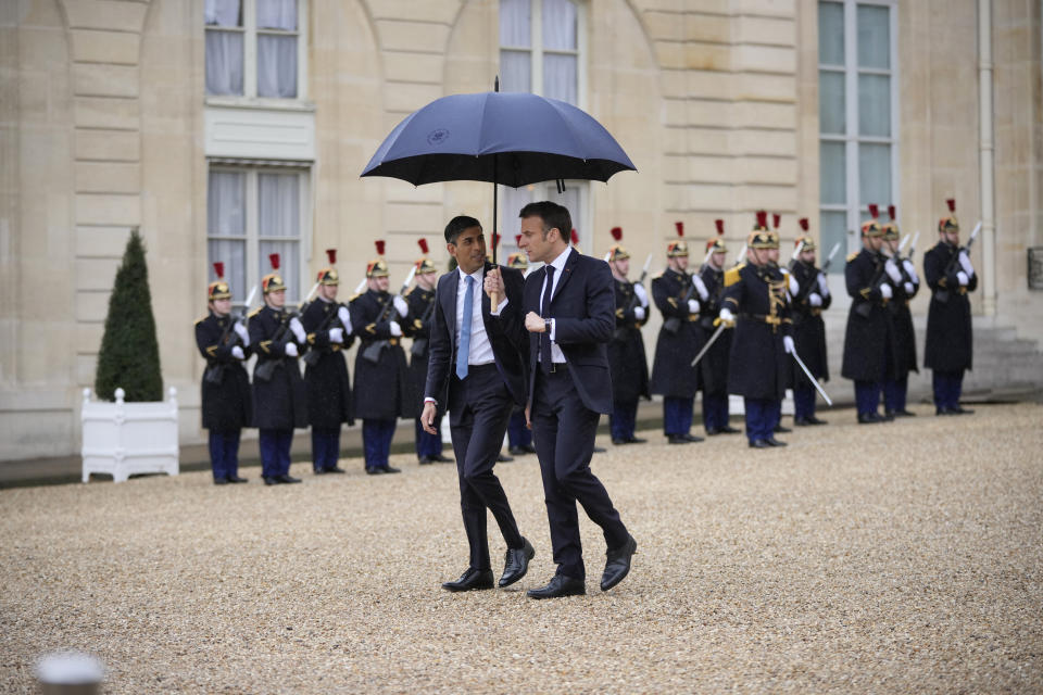 French President Emmanuel Macron, centre right, uses an umbrella to protect Britain's Prime Minister Rishi Sunak after a French-British summit at the Elysee Palace in Paris, Friday, March 10, 2023. French President Emmanuel Macron and British Prime Minister Rishi Sunak meet Friday in Paris in a summit aimed at mending relations following post-Brexit tensions, improving military and business ties and toughening efforts against Channel migrant crossings. (AP Photo/Kin Cheung, Pool)
