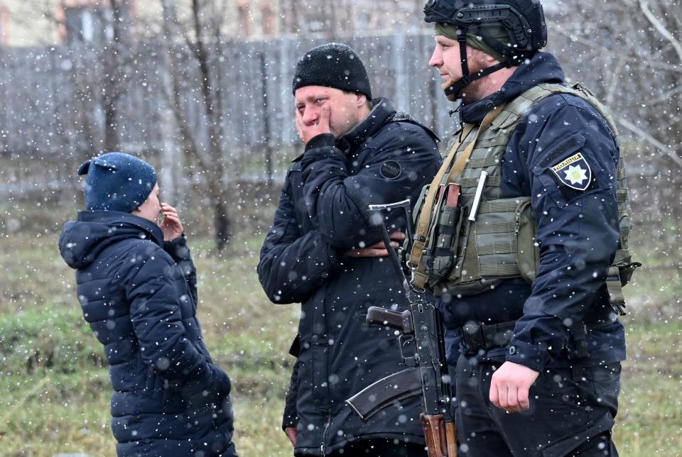 TOPSHOT - People react as they gather close to a mass grave in the town of Bucha, just northwest of the Ukrainian capital Kyiv on April 3, 2022. - President Volodymyr Zelensky accused Russia of committing genocide and attempting to eliminate the 