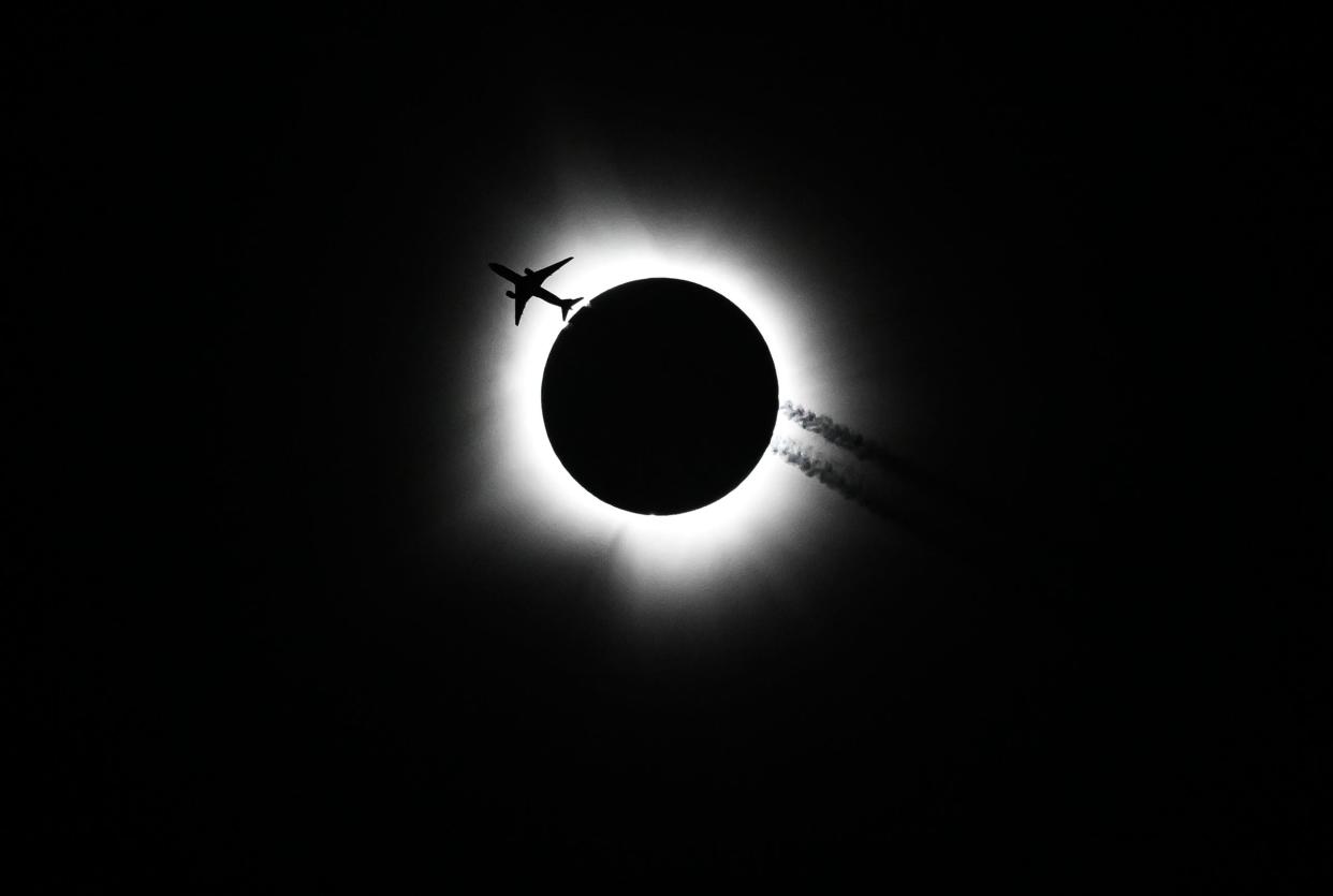 An airplane passes near the eclipse during the Hoosier Cosmic Celebration at Memorial Stadium on Monday, April 8, 2024.