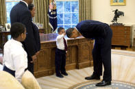 Sur la photo de ce dépliant, prise à Washington le 8 mai 2009 et publiée plus tard par la Maison-Blanche, le Président Barack Obama se penche en avant afin que le fils d’un membre du personnel de la Maison-Blanche puisse tapoter sa tête lors d’une visite en famille du Bureau ovale. REUTERS/Pete Souza/The White House/Handou