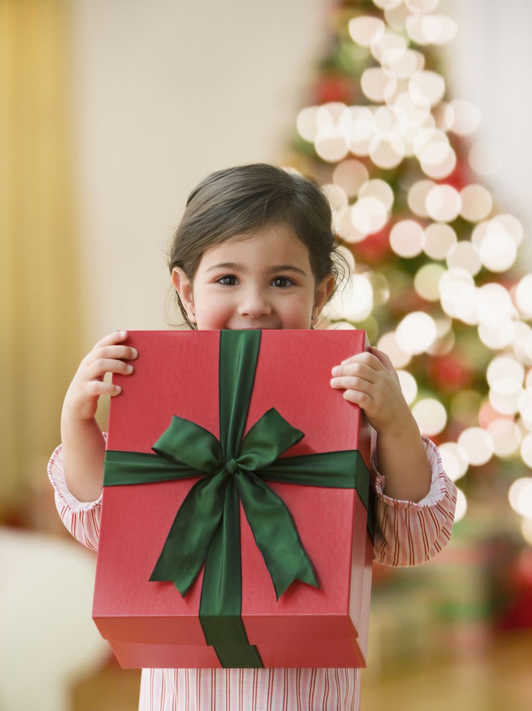 curious young girl holding large christmas gift