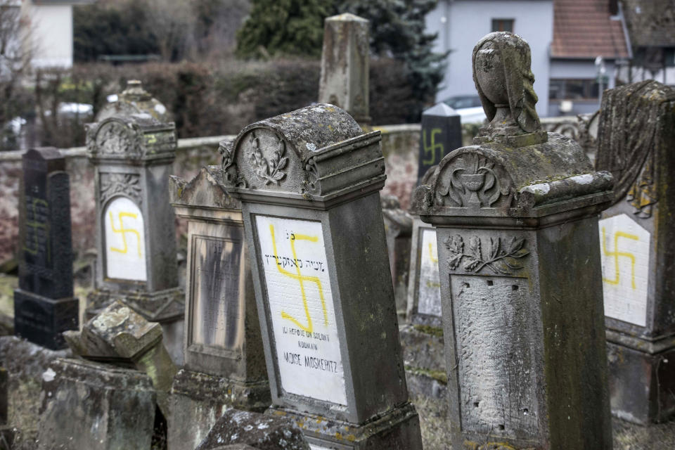 Vandalized tombs with tagged swastikas are pictured in the Jewish cemetery of Quatzenheim, eastern France, Tuesday, Feb.19, 2019. Marches and gatherings against anti-Semitism are taking place across France following a series of anti-Semitic acts that shocked the country. (AP Photo/Jean-Francois Badias)