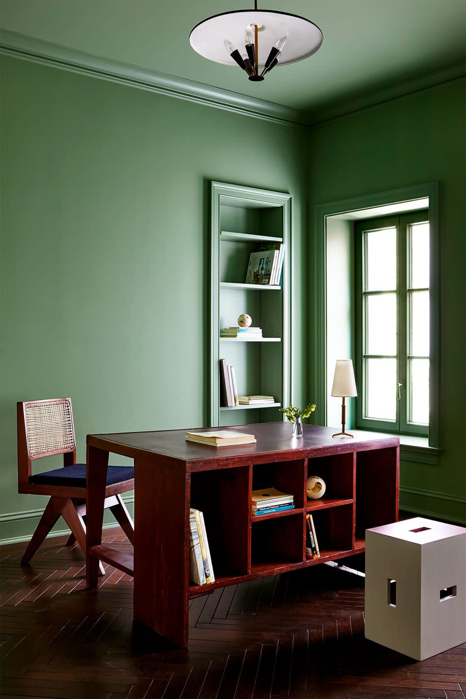 a green room with a table and chairs and a beautiful overhead light fixture