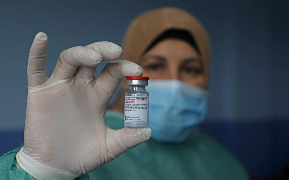 A Palestinian health worker holds a vial of Covid-19 vaccine at the Palestine Red Crescent hospital - Jaafar Ashtiyeh/AFP